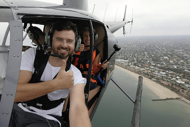 Happy passengers wearing headsets during helicopter flight with scenic coastal view